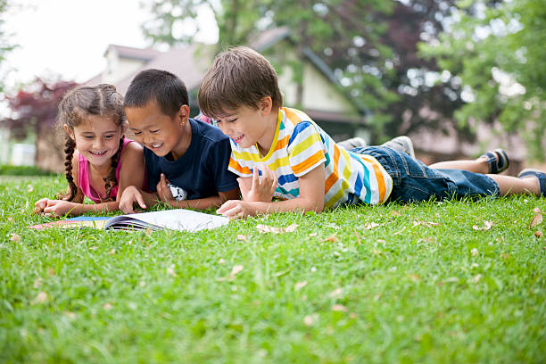 Elementary Aged Children Reading A Book In The Park